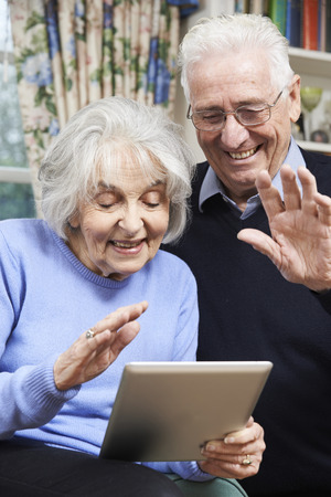 Senior Couple Using Digital Tablet For Video Call With Familyの写真素材