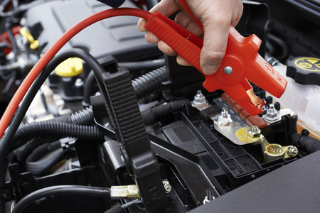 Close-Up Of Mechanic Attaching Jumper Cables To Car Battery
