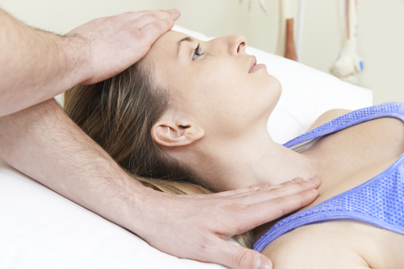Male Osteopath Treating Female Patient With Neck Problemの写真素材