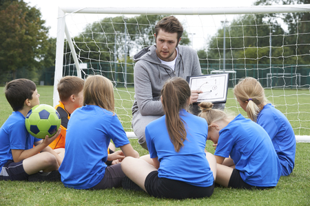 Coach Giving Team Talk To Elementary School Soccer Team Coach Giving Team Talk To Elementary School Soccer Team