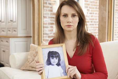 Unhappy Mature Woman With Photograph Of Daughter In Frame
