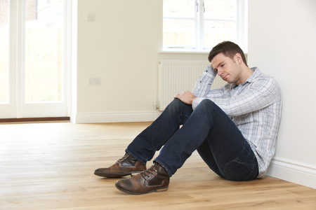 Depressed Man Sitting In Empty Room Of Repossessed Houseの写真素材