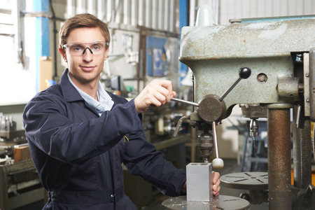 Engineer Using Drill In Factory Workshop