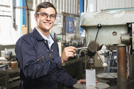 Teenage Apprentice Operating Machinery In Factoryの写真素材