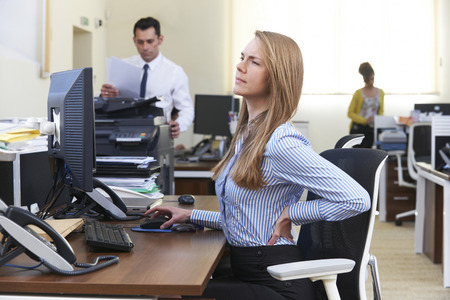 Businesswoman Working At Desk Suffering From Backacheの写真素材