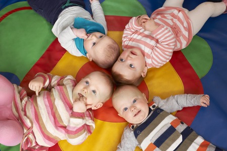 Overhead View Of Babies Lying On Mat At Playgroupの写真素材