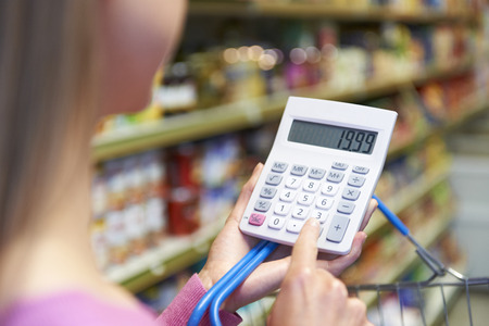 Woman Using Calculator To Cost Shopping In Supermarketの写真素材