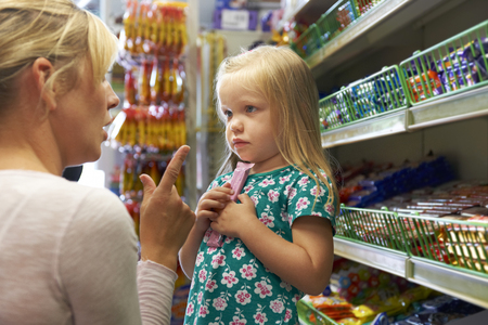 Girl Having Arguement With Mother At Candy Counter In Supermarkeの写真素材
