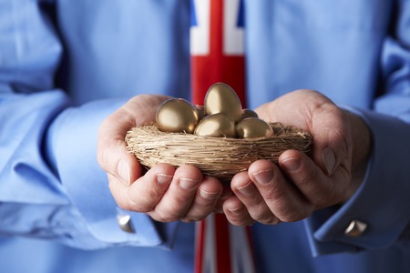 Businessman Wearing Union Jack Tie Holding Nest Of Golden Eggsの写真素材