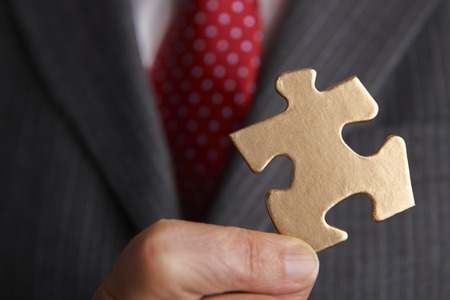 Businessman Holding Golden Jigsaw Pieceの写真素材