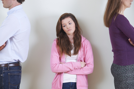 Teenage Girl Standing Between Parents Not Speaking To Each Otherの写真素材