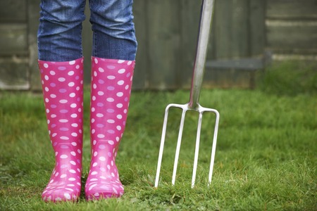 Close Up Of Woman Wearing Pink Wellingtons Holding Garden Forkの写真素材