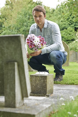 Man Laying Flowers At Graveの写真素材