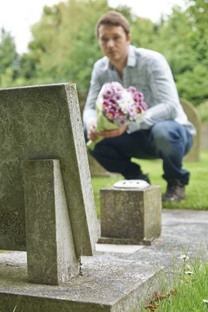 Man Laying Flowers On Graveの写真素材