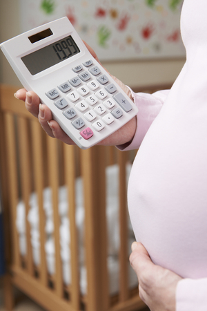 Pregnant Woman In Nursery With Calculatorの写真素材