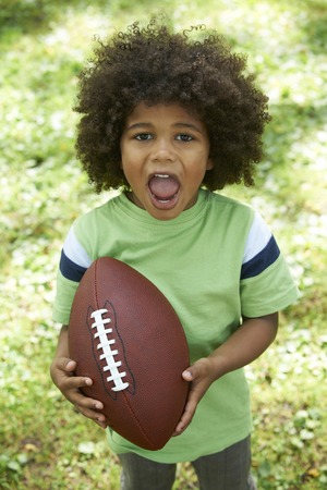 Excited Young Boy Playing American Football In Parkの写真素材
