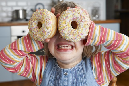 Girl Making Glasses Using Sugary Doughnutsの写真素材