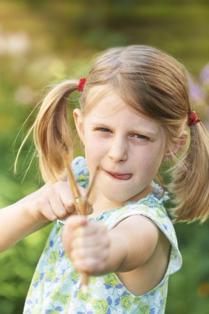 Girl Aiming Slingshot At Camera