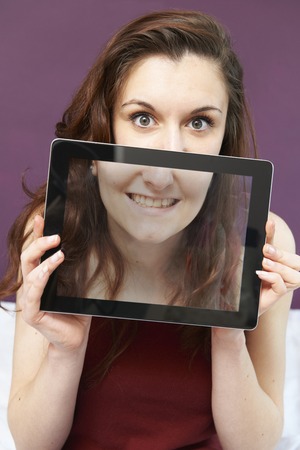 Smiling Teenage Girl Holding Digital Tablet In Front Of Faceの写真素材