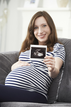 Portrait Of Pregnant Woman Holding Ultrasound Scan Of Babyの写真素材