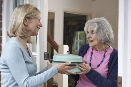 Woman Bringing Meal For Elderly Neighbourの写真素材