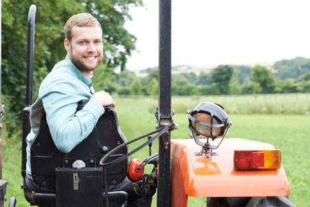 Portrait Of Farmer Sitting On Tractor In Field