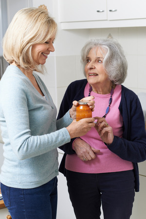 Woman Helping Senior Neighbor To Remove Jar Lidの写真素材
