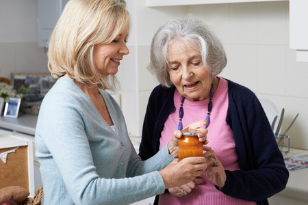 Woman Helping Senior Neighbor To Remove Jar Lidの写真素材