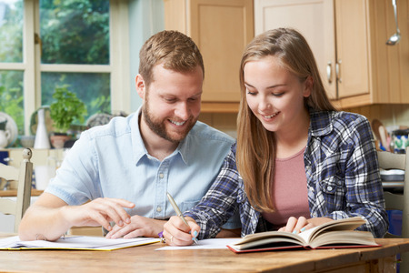 Male Home Tutor Helping Teenage Girl With Studiesの写真素材