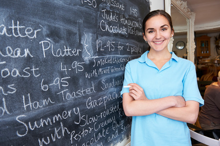 Waitress In Restaurant Writing Menu On Blackboardの写真素材