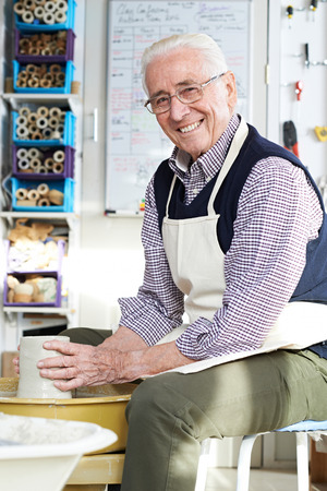 Senior Man Working At Pottery Wheel In Studioの写真素材
