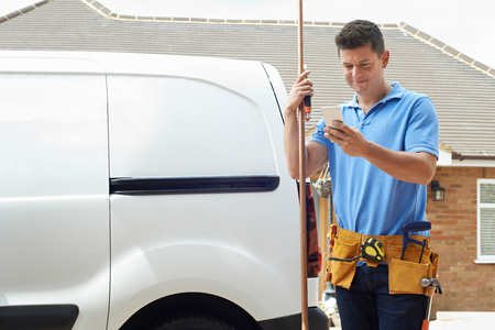 Plumber With Van Using Mobile Phone Outside Houseの写真素材