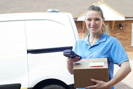 Portrait Of Female Courier With Van Delivering Package To Houseの写真素材