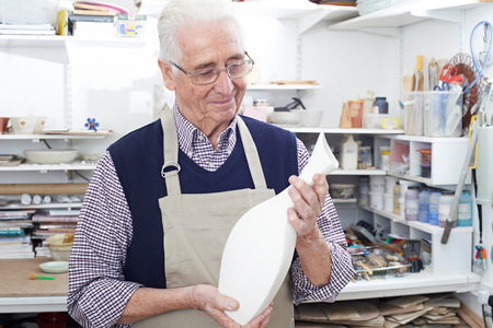 Senior Man Holding Vase In Pottery Studioの写真素材