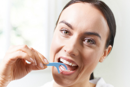 Young Woman Flossing Teeth In Bathroomの写真素材
