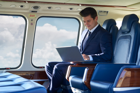 Businessman Working On Laptop In Helicopter Cabin During Flightの写真素材