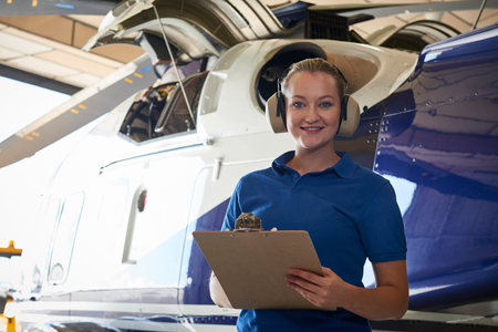 Portrait Of Female Aero Engineer With Clipboard Carrying Out Check On Helicopter In Hangarの写真素材