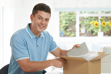 Man At Home Unwrapping Digital Tablet Bought Onlineの写真素材