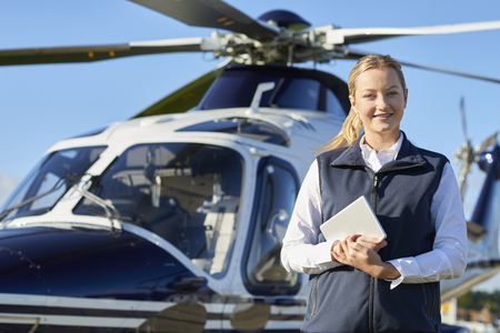 Portrait Of Female Pilot Standing In Front Of Helicopter With Digital Tabletの写真素材