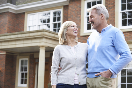 Smiling Mature Couple Standing Outside Homeの写真素材