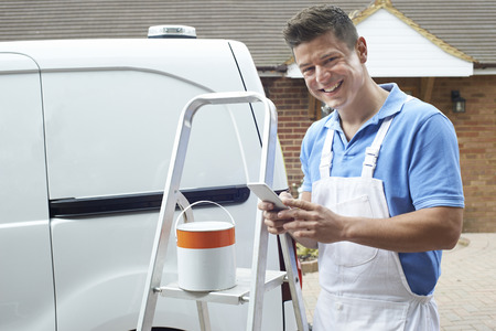 Decorator Using Mobile Phone Standing Outside Domestic Homeの写真素材
