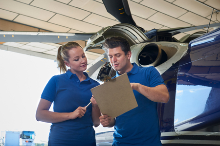 Aero Engineer And Apprentice Working On Helicopter In Hangar Looking At Clipboardの写真素材