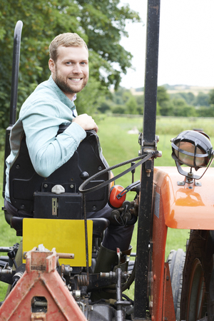 Portrait Of Farmer Sitting On Tractor In Fieldの写真素材