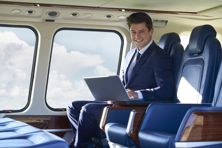 Portrait Of Businessman Working On Laptop In Helicopter Cabin During Flightの写真素材