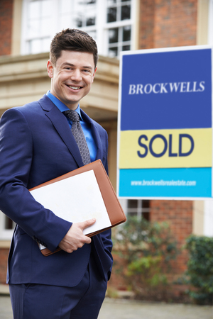Male Realtor Standing Outside Residential Property With Sold Signの写真素材
