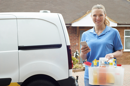 Portrait Of Woman Running Mobile Cleaning Business Checking Text Messagesの写真素材