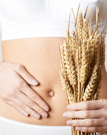 Close Up Of Woman Wearing Underwear Holding Bundle Of Wheat And Touching Stomachの写真素材