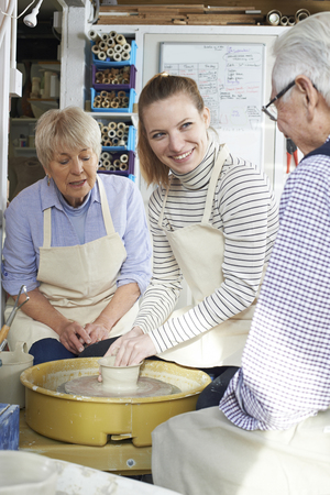 Senior Couple With Teacher In Pottery Classの写真素材