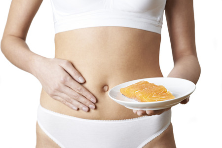 Woman In Underwear holding a plate of Salmon And Touching Stomachの写真素材