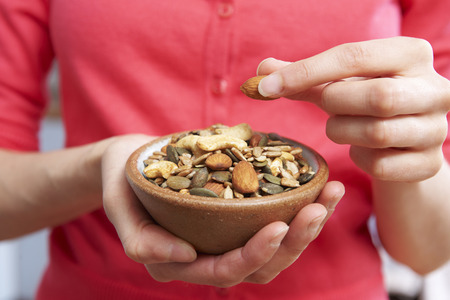 Close Up Of Woman Eating Bowl Of Healthy Nuts And Seedsの写真素材